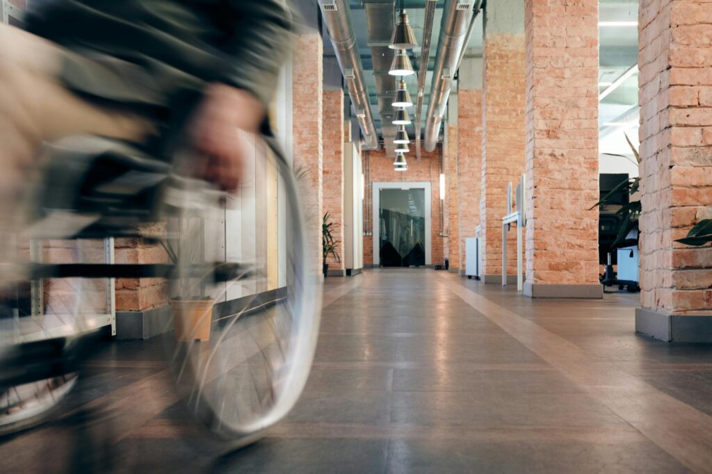Blurred motion of wheelchair in a modern office hallway, highlighting accessibility.