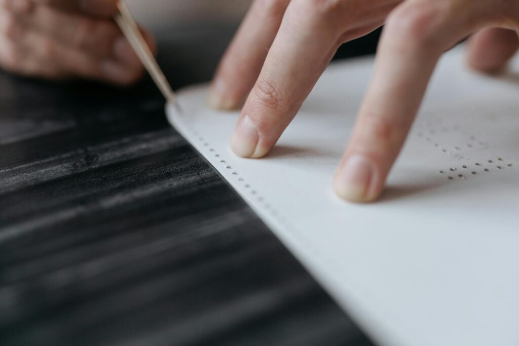 Detailed shot of hands creating a Braille document, illustrating tactile learning.